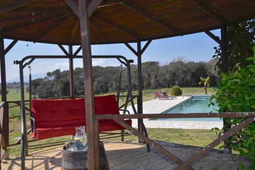 a red chair under a gazebo next to a pool at B&B El Ranxo in Franciach