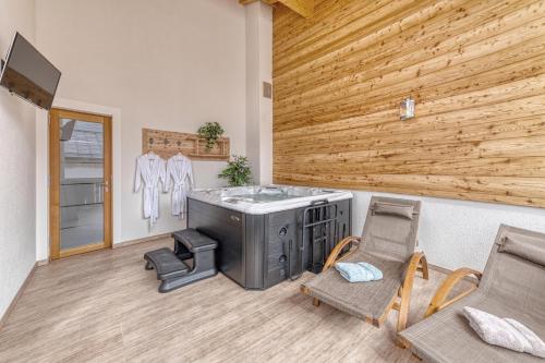 een kamer met een hot tub, stoelen en een houten muur bij Pension und Ferienchalets Zum Lebzelter in Freyung