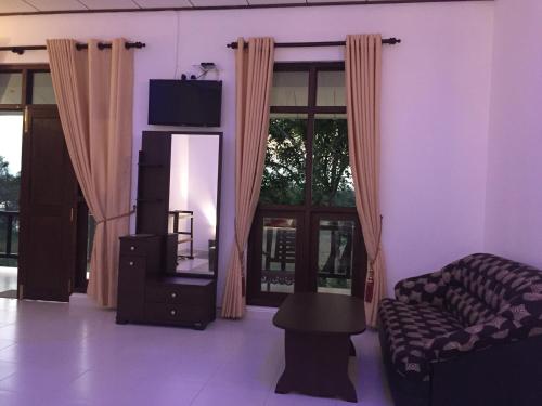 een woonkamer met een bank en een spiegel bij Goddess Garden Sigiriya in Sigiriya