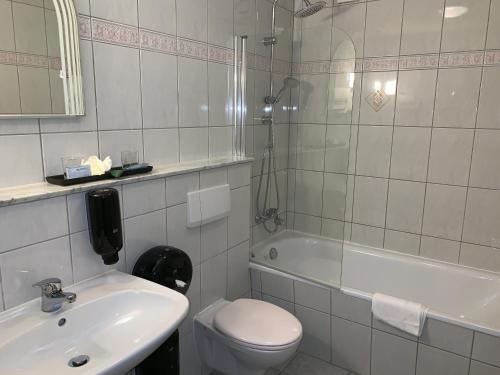 a bathroom with a sink and a toilet and a tub at Hotel Haus Hubertus in Elsdorf