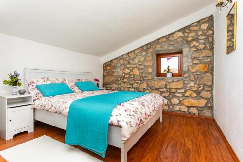 a bedroom with a bed and a stone wall at Villa Korina in Pinezici