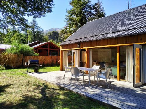una casa con una mesa y sillas en una terraza en BOG El Granero, en Villa La Angostura