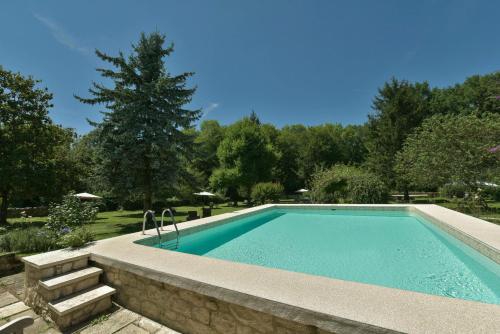 a swimming pool with a stone wall around it at Le Prieuré Le Pavillon in Souillac
