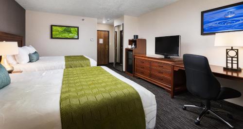 a hotel room with a bed and a desk with a television at Best Western Plus Landmark Inn in Park City