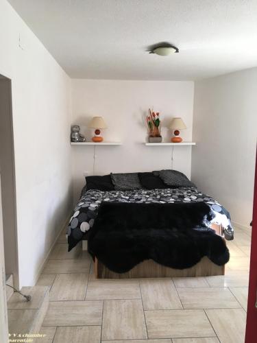 a bedroom with a black bed in a white room at VVA in Conques-sur-Orbiel