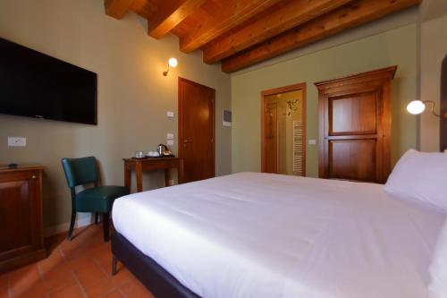 a bedroom with a large white bed and a television at La Boheme Chambres in Lazise