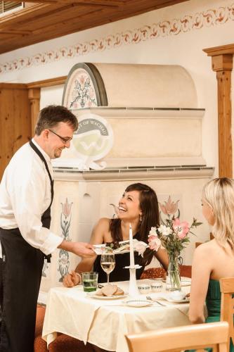 a man feeding a woman a plate of food at a table at Landhotel Wachau - Hotel Garni in Emmersdorf an der Donau