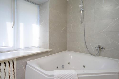 a white bath tub in a bathroom with a shower at Arena Summit Apart Hotel in Kyiv