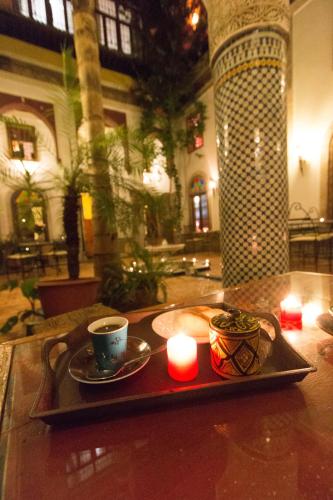 a tray with a cup of coffee and a candle at Riad El Ma in Meknès