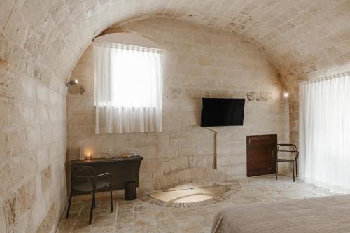 a bedroom with a bed and a tv on a wall at Cenobio Hotel & SPA Matera in Matera