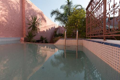 a swimming pool next to a pink building at Riad El Ma in Meknès