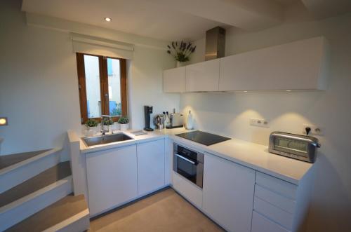 une cuisine blanche avec des armoires blanches et un évier dans l'établissement Ramatuelle Maison de Village, à Ramatuelle