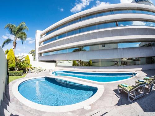 um edifício com duas piscinas em frente em Hotel Mercury Inn em Querétaro