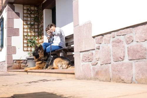 a woman sitting on a porch with a dog on a leash at Markulluko Borda Rural Suites in Elizondo