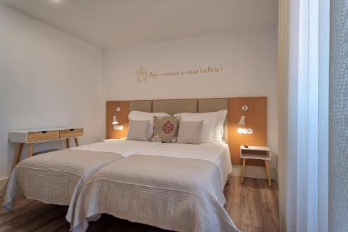 a bedroom with a large bed with white sheets at Alojamento da Vila in Valença