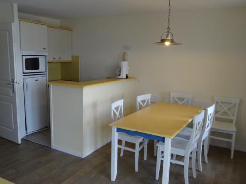 eine Küche mit einem Tisch und Stühlen sowie einem Kühlschrank in der Unterkunft Cap Morgat in Crozon
