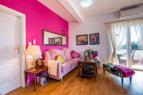 a pink living room with a couch and a table at Maja Apartment Cavtat II in Cavtat