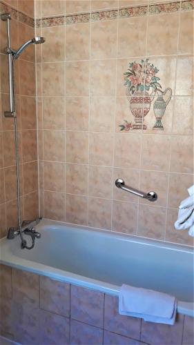 a bath tub in a bathroom with a tile wall at Hotel Le Reynita in Trouville-sur-Mer