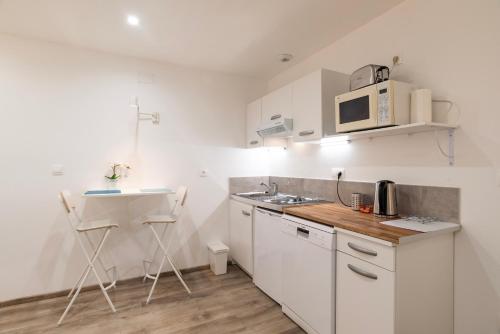 a white kitchen with a sink and a microwave at CityCosy Strasbourg - Studio Hirtz Orangerie in Strasbourg