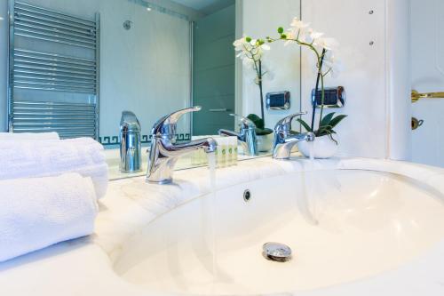 un lavandino in bagno con due rubinetti e uno specchio di Cagliari Upper House a Cagliari