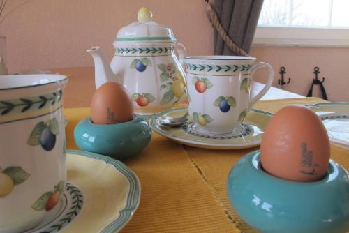 a table with eggs sitting in cups and plates at Hummerstübchen Morsum in Morsum