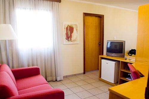 a living room with a red couch and a television at Hotel O Casarão in Araras