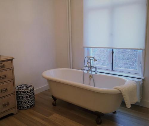 uma banheira branca na casa de banho com uma janela em NineT7 em Tilburgo