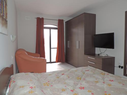 a bedroom with a bed and a dresser and a television at Antros, Apartment 1 in Xlendi