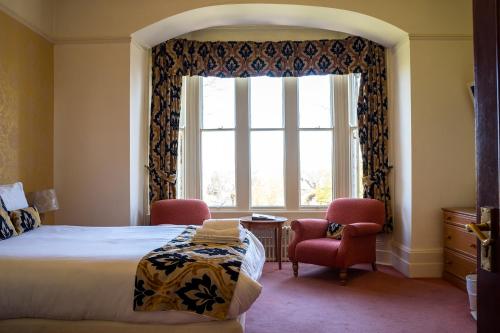 a bedroom with a bed and two chairs and a window at Farnley Tower Guesthouse in Durham