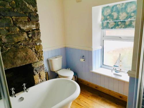baño con bañera, aseo y ventana en Pen-y-Patch, en Prestatyn