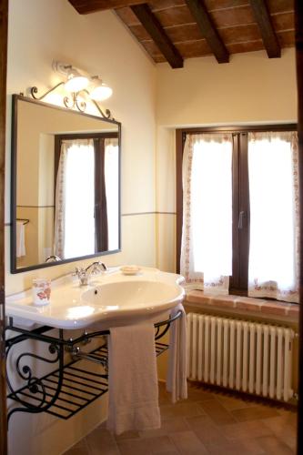 a bathroom with a sink and a mirror and two windows at FATTORIA DELLA BILANCIA in San Giovanni in Marignano