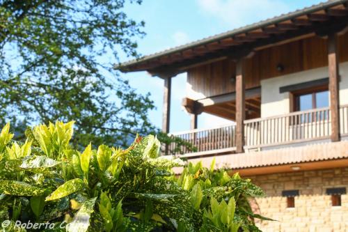 a building with a balcony and trees in front of it at Artesoro Baserria in San Pedro de Galdames