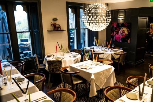 a restaurant with white tables and chairs and a chandelier at Farnley Tower Guesthouse in Durham