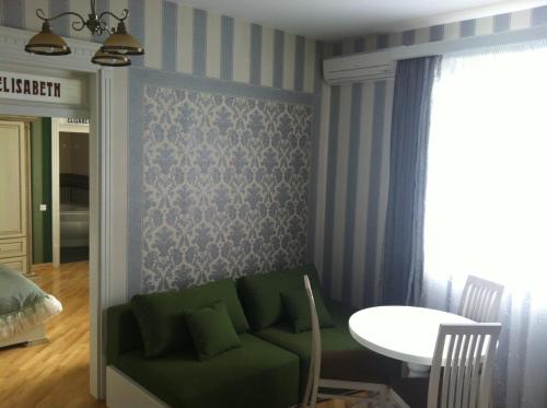 a living room with a green couch and a table at Fontush Boutique Hotel in Ivano-Frankivsʼk