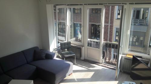a living room with a couch and some windows at Arno's Place in Ostend