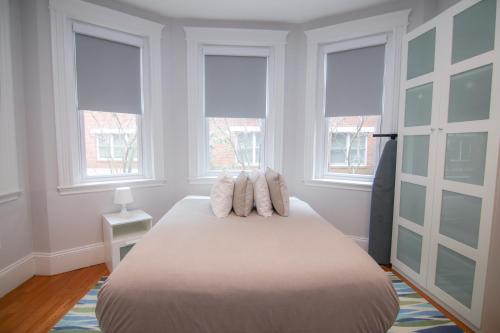 a bedroom with a bed with three pillows on it at A Stylish Stay w/ a Queen Bed, Heated Floors.. #14 in Brookline