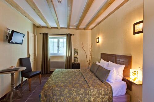 a hotel room with a bed and a window at Hotel-restaurant Les Caudalies in Arbois