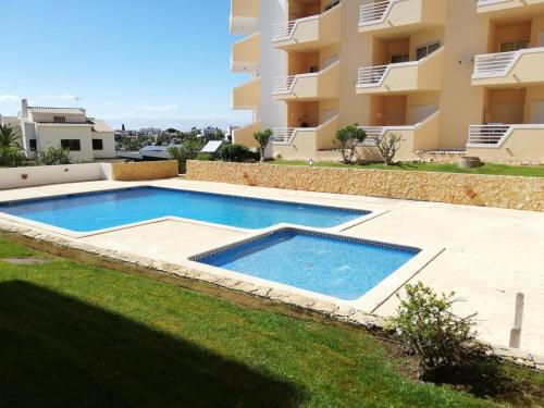 a swimming pool in a yard next to a building at Amoreira Alvor - Praia e Piscina in Alvor