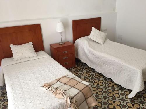 a bedroom with two beds and a table with a lamp at La Casa del Mar in Garachico