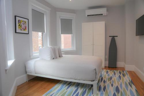 a bedroom with a white bed and two windows at A Stylish Stay w/ a Queen Bed, Heated Floors.. #32 in Brookline