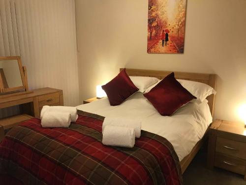 a bedroom with a large bed with red and white pillows at exploreNESS Apartment in Inverness
