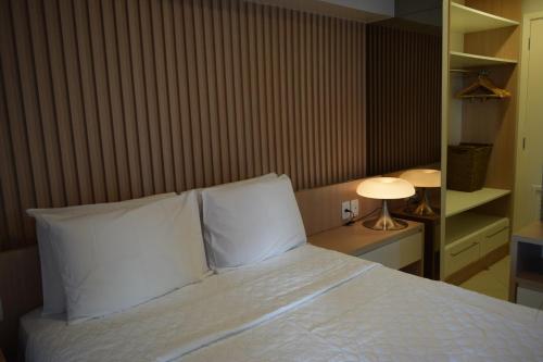 a bedroom with a bed with white pillows and a lamp at Grupo Vip Landscape Fortaleza in Fortaleza