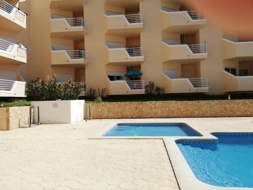 an apartment with a swimming pool in front of a building at Amoreira Alvor - Praia e Piscina in Alvor