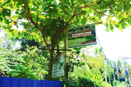 a sign on a tree that says paradise on it at Lake view cabana Paradise & Villa in Tangalle