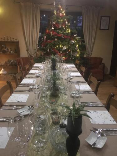 a long table with wine glasses and a christmas tree at l'émiline in Gouvy