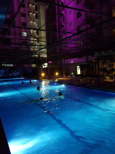 a group of people swimming in a swimming pool at night at Horizon 101 Cebu by KC Condo in Cebu City