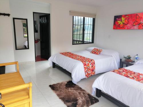 a hotel room with two beds and a mirror at Hotel Campestre El Triunfo in San Agustín