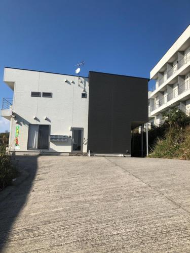 a white building with a parking lot in front of it at VistaMare in Kanoya