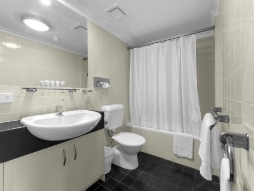 a white bathroom with a sink and a toilet at Central Brunswick Apartment Hotel in Brisbane