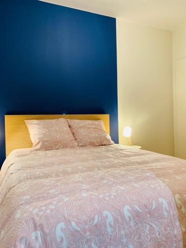 une chambre avec un grand lit avec un mur bleu dans l'établissement Esprit Cosy sur plateau central, à Clermont-Ferrand